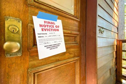 Eviction notice taped to a wooden door of a house